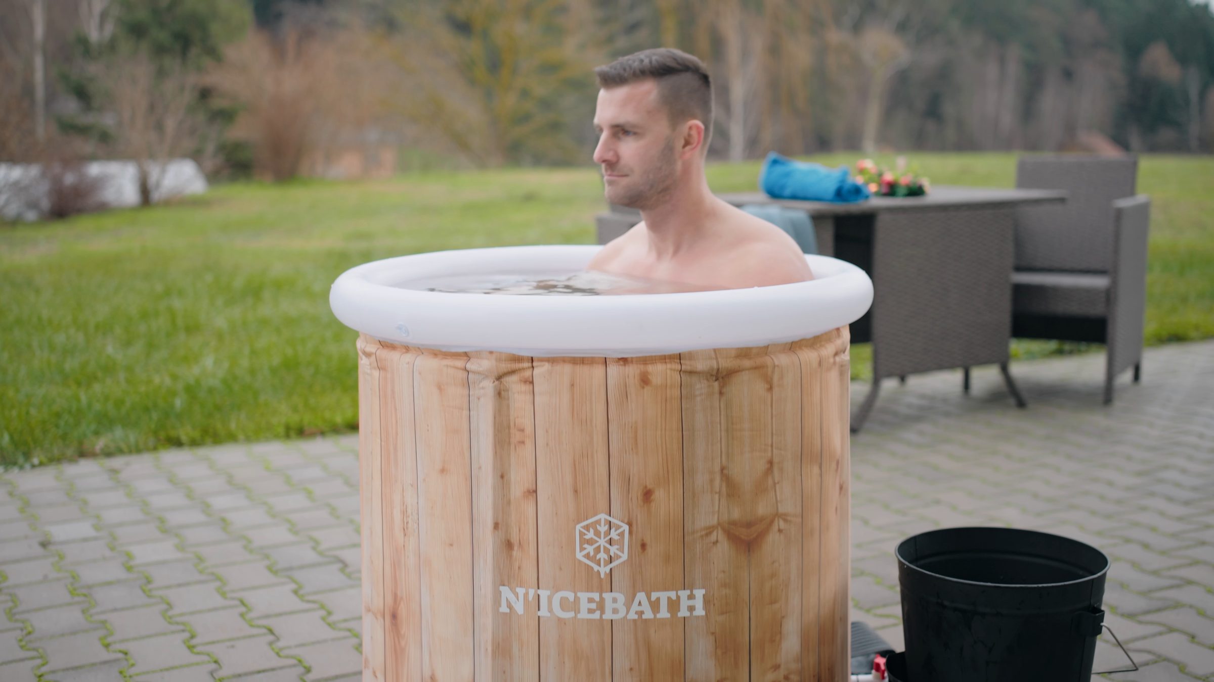 Mann sitzt entspannt im RefreshPod im Garten und schaut in die Ferne